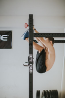 Atleta de lado haciendo toes to bar en un rack de crossfit