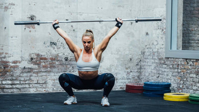 Mujer haciendo un overhead squat con una barra de crossfit